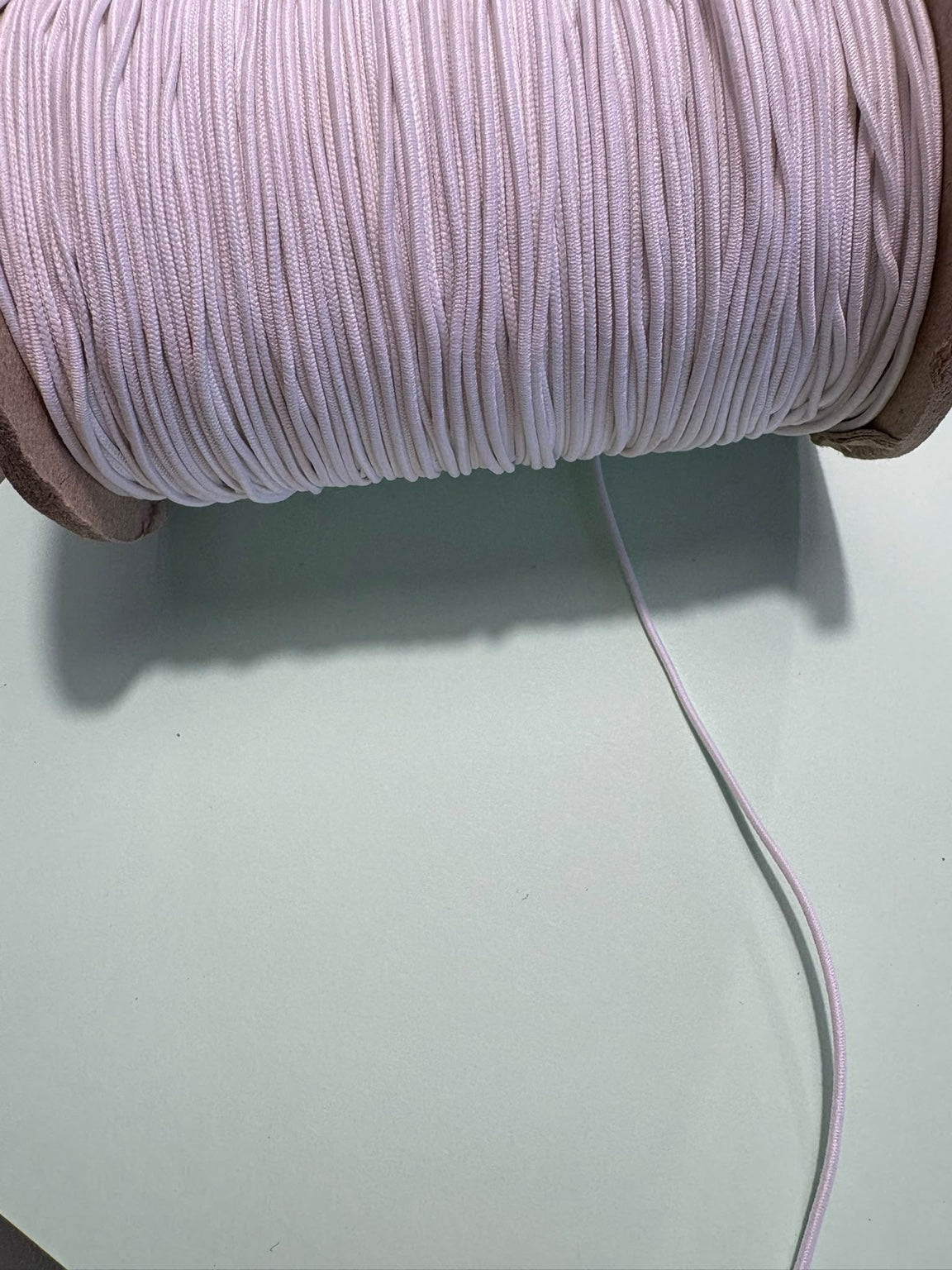 White 1mm cord elastic, close-up of fine round elastic cord on a reel