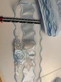Pale blue satin embroidered trim 100mm wide with rose and floral motif and wavy edges, shown with a ruler for scale