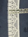 White flat lace trim 20mm wide with open floral pattern and picot edges, shown on denim fabric with a ruler for scale