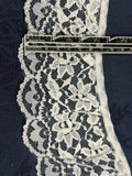 White gathered lace trim 80mm wide with full floral and leaf pattern and scalloped edge, shown on denim fabric with a ruler for scale