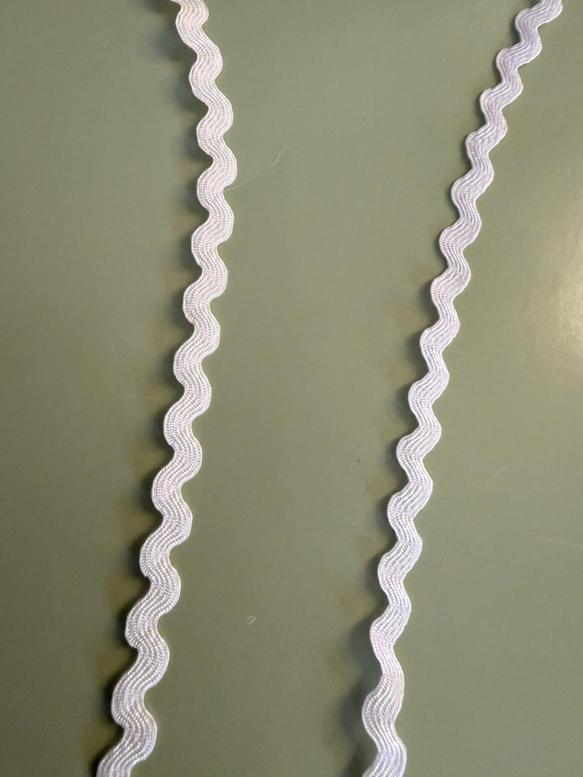 Pink ric rac trim 5mm wide with classic zigzag wave, shown on green background
