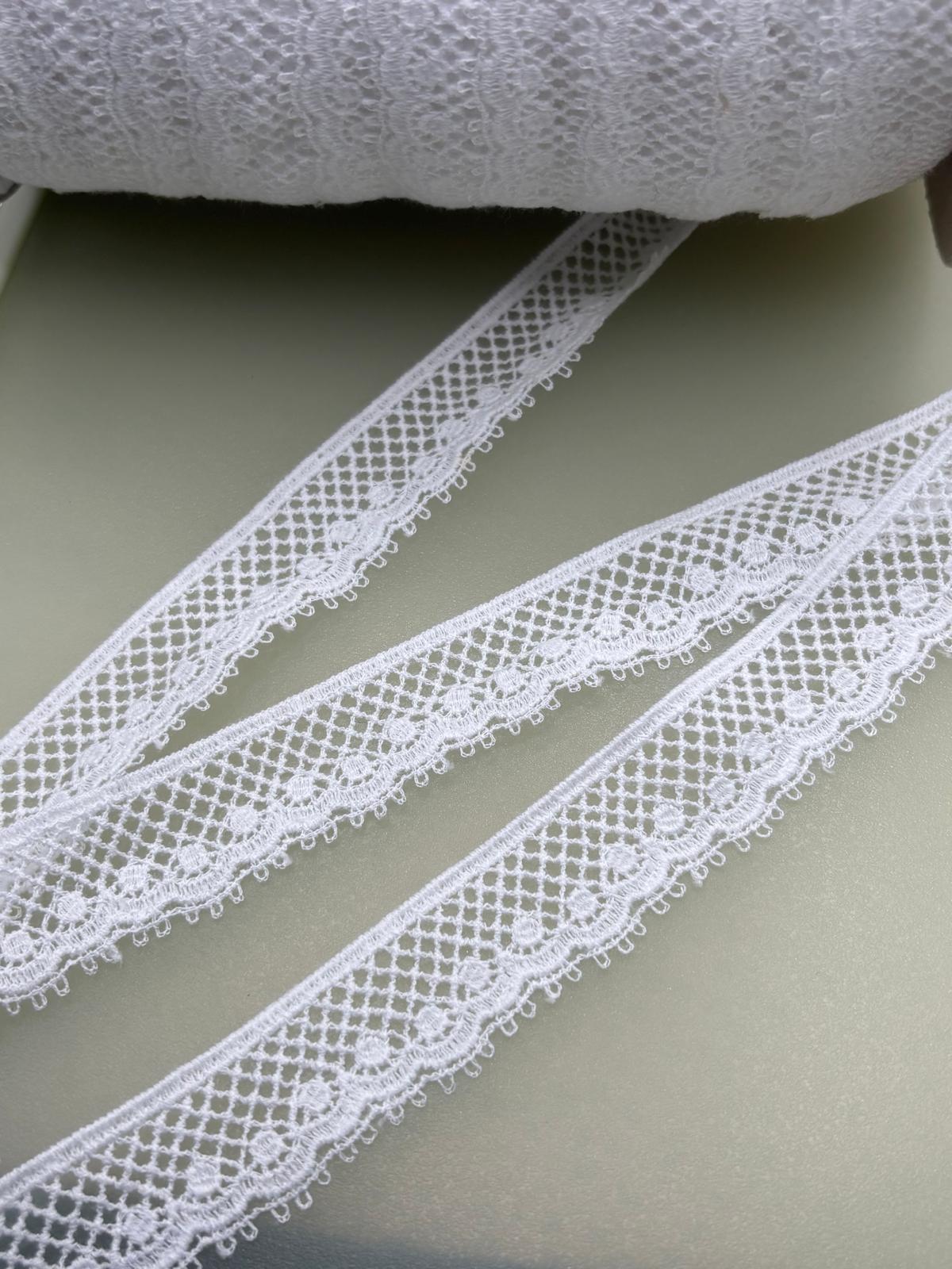 White cotton couture lace with openwork floral pattern and decorative edge, approximately 25mm wide